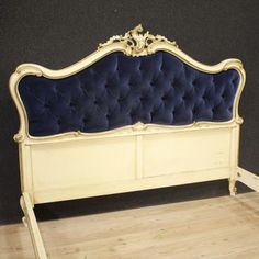 an antique style bed frame with blue velvet upholstered headboard