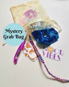 the contents of a mystery grab bag on a white table with blue ribbon and stickers