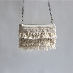 Our fun and flirty crossbody bag is perfect for beachy vacations and casual Summer travels. A tassel fringe trim on one side paired with a sleek silver chain crossbody strap in a slim profile that is perfect for carrying just the essentials. DetailsMini size exterior dimensions are 7.5in L x 5in HNatural canvas exteriorCotton fringe trim on one side (back is canvas)48 inch crossbody length. Flat sided chain for comfortable carry.Lined in a bold tropical print7 inch zippered closureDurably handcr Trendy Beach Crossbody Clutch, Trendy Crossbody Clutch For The Beach, Summer Crossbody Clutch With Chain Strap, Summer Clutch With Chain Strap, Summer Fringe Crossbody Bag, Summer Beach Crossbody Clutch, Beach Clutch With Fringe, Rectangular, Bohemian Summer Clutch With Tassels, Vacation Tassel Clutch Bags