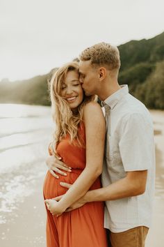 a pregnant couple embracing on the beach