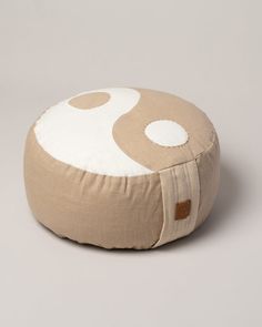 a beige and white round cushion with circles on the front, sitting on a gray background