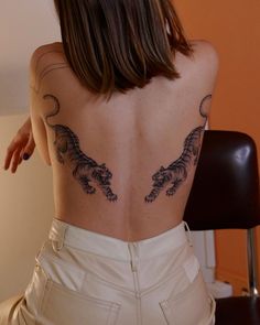 the back of a woman's body with tattoos on it