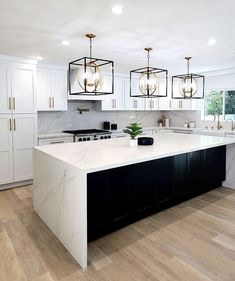 a large kitchen with white cabinets and marble counter tops, an island in the middle