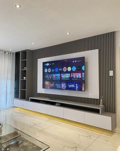 a large flat screen tv mounted on the wall in a living room next to a glass coffee table