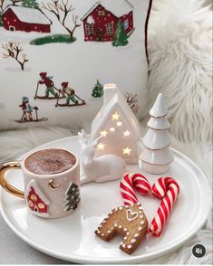 a white plate topped with a cup of hot chocolate next to a gingerbread christmas tree