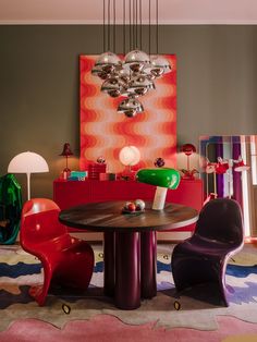 a dining room table with chairs around it and an art work on the wall in the background