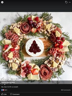 a wreath made out of cheese, meats and fruit on a marble counter top