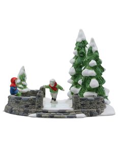 a figurine of two children playing in the snow with trees and rocks behind them