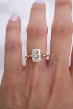 a woman's hand with a diamond ring on top of her finger and an engagement band