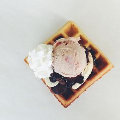 a waffle topped with ice cream and blueberries sitting on top of a white table