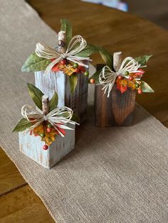 two small wooden blocks decorated with fall leaves and twine bows on top of a table