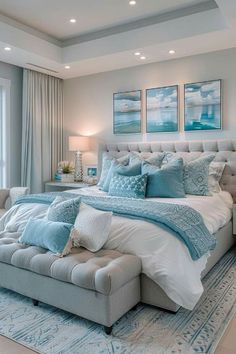 a large bed sitting in a bedroom next to a window covered in blue and white pillows