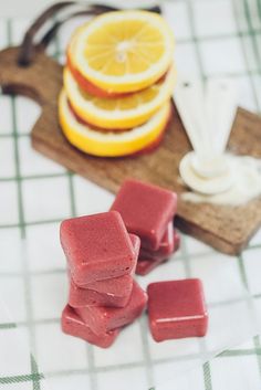 sliced oranges and cubes of soap on a cutting board next to some fruit