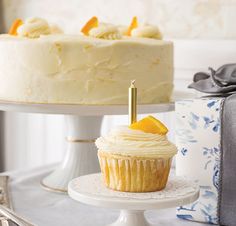 a white cake sitting on top of a table next to a silver plate with a cupcake