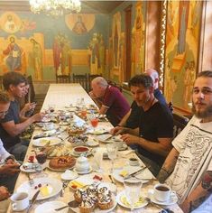 a group of people sitting at a long table with plates of food in front of them