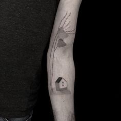 a man's arm with a house and flowers tattoo on the left inner arm