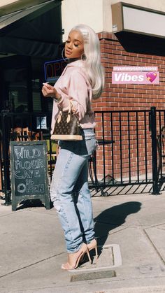 a woman with white hair is standing on the sidewalk