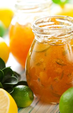 there are many lemons and limes next to the jars with liquid in them