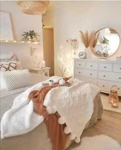 a bedroom with white furniture and lights on the wall, along with a bed covered in blankets