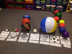 an assortment of sports balls and other items on the floor in a classroom setting,