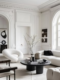 an elegant living room with white walls and black tables in front of the couches