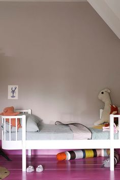 a white bed sitting in a bedroom on top of a hard wood floor next to a stuffed animal