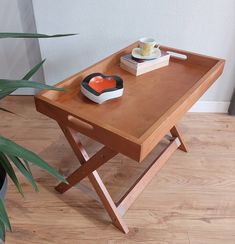 a wooden table with a heart shaped plate on it next to a potted plant