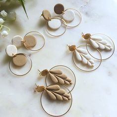 four pairs of gold hoop earrings with white and grey stones on them sitting on a marble surface