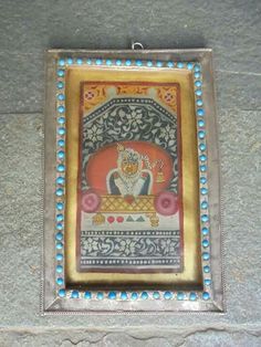 a painting on the wall with beads around it's edges and an ornate frame