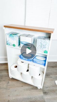 an open cabinet with toilet paper and other items on the shelf in front of it