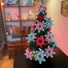 a small christmas tree decorated with red, white and green snowflakes on a table