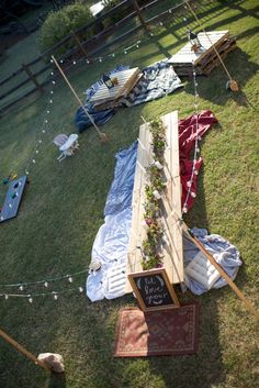 an overhead view of a picnic area with blankets and flowers on the grass, tables and chairs in the background