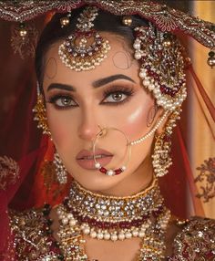 a woman in a bridal outfit with jewelry on her head and veil over her face