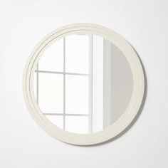 a white round mirror hanging on the wall next to a window with an open door