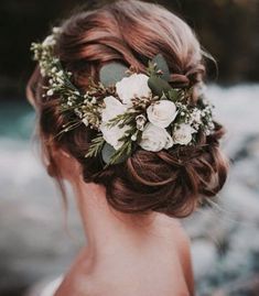 a woman with flowers in her hair is looking at the water and rocks behind her