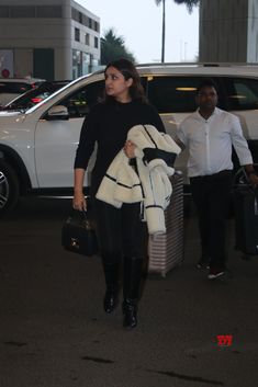 a woman in black and white coat carrying luggage