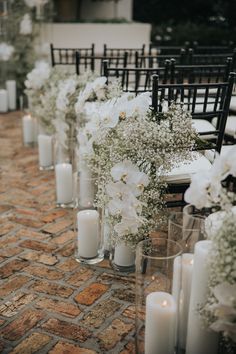 rows of chairs with white flowers and candles