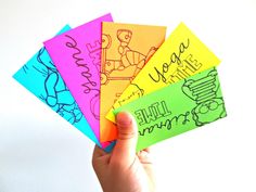 a hand holding five different colored papers with writing on them