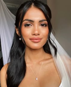 a woman with long hair wearing a wedding dress and veil, posing for the camera