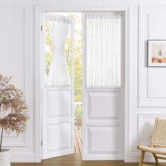 an open door with white curtains and a chair in the foreground, near a window