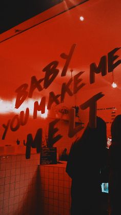 people standing in front of a red wall with writing on it that says baby, me you make me feel me