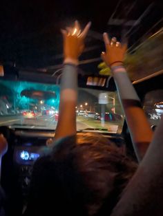 two people in the back seat of a car with their hands up and lights on