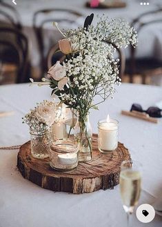 there is a vase with flowers and candles in it on a wooden slice at the table