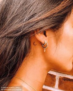 a close up of a woman's ear with two small hoops on it