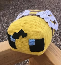 a crocheted yellow purse sitting on top of a wooden bench