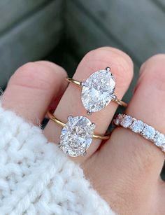 a woman's hand holding three diamond engagement rings