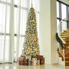 a decorated christmas tree sitting in the middle of a living room next to a stair case