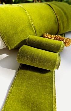 a close up of a green tie on a white table with flowers in the background