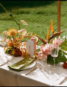 the table is set with flowers and place settings for guests to sit down at it