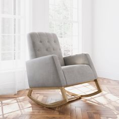 a gray rocking chair sitting on top of a hard wood floor next to a window